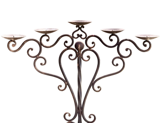 Wrought iron pricket candelabra, close-up of five scrolled arms and drip pans