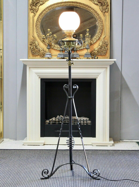 Arts & Crafts style wrought iron and brass rise and fall standard lamp with white glass globe shade and scrolled tripod base