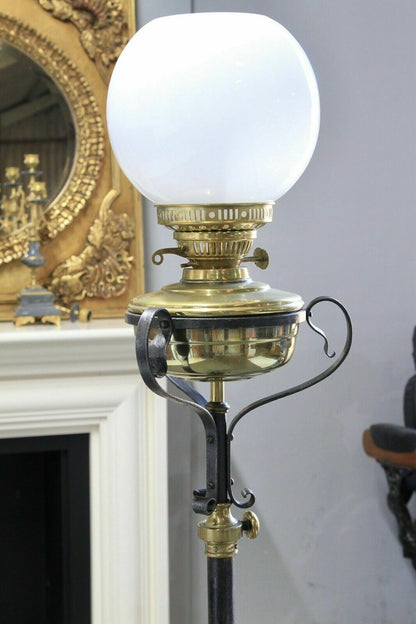 Close-up of brass oil-lamp-style fitting and white glass globe, wrought iron standard lamp