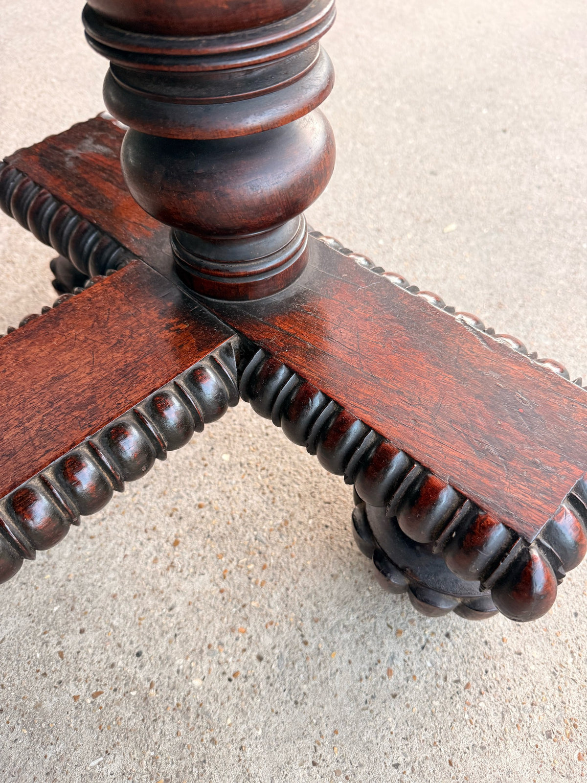 Close-up of one end support: turned column on a gadrooned platform with lobed bun feet