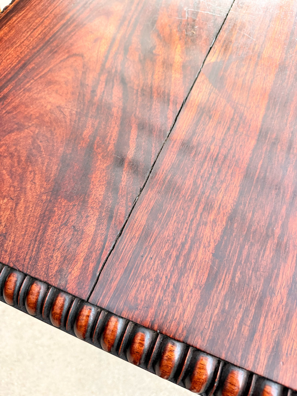 Close-up of the figured rosewood top showing the board joint where it meets the gadrooned edge