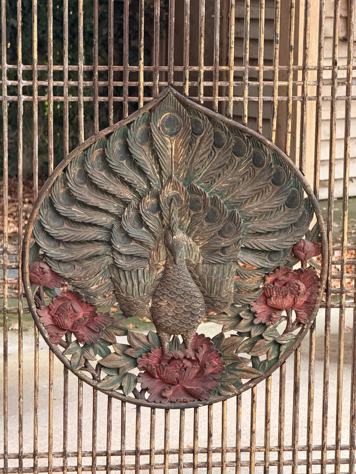 Close-up of carved peacock medallion with red painted peonies and gilt highlights