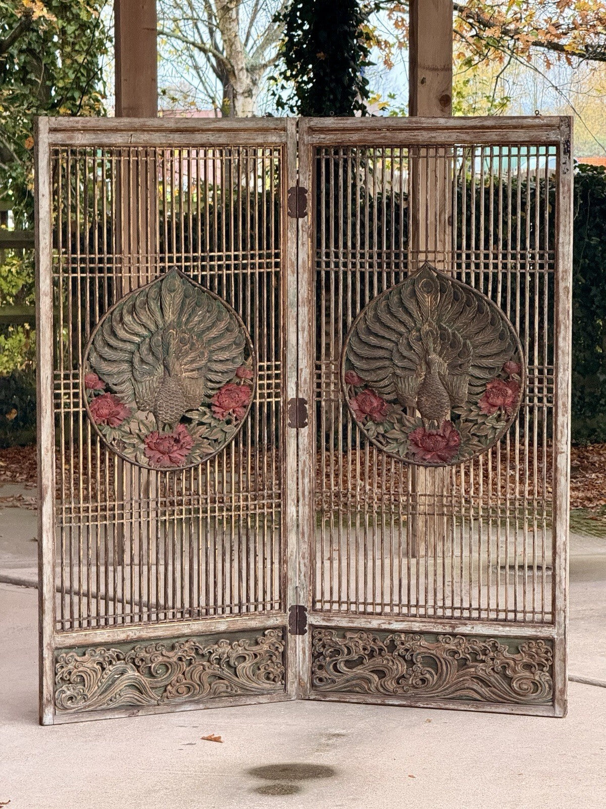 Antique two-panel lattice screen with carved peacock medallions, red flowers and carved wave base panels