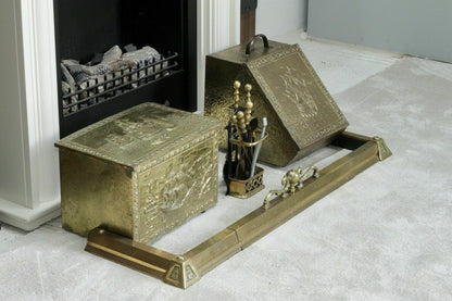 Brass hearth fender styled with a brass coal box and fire tools by a fireplace