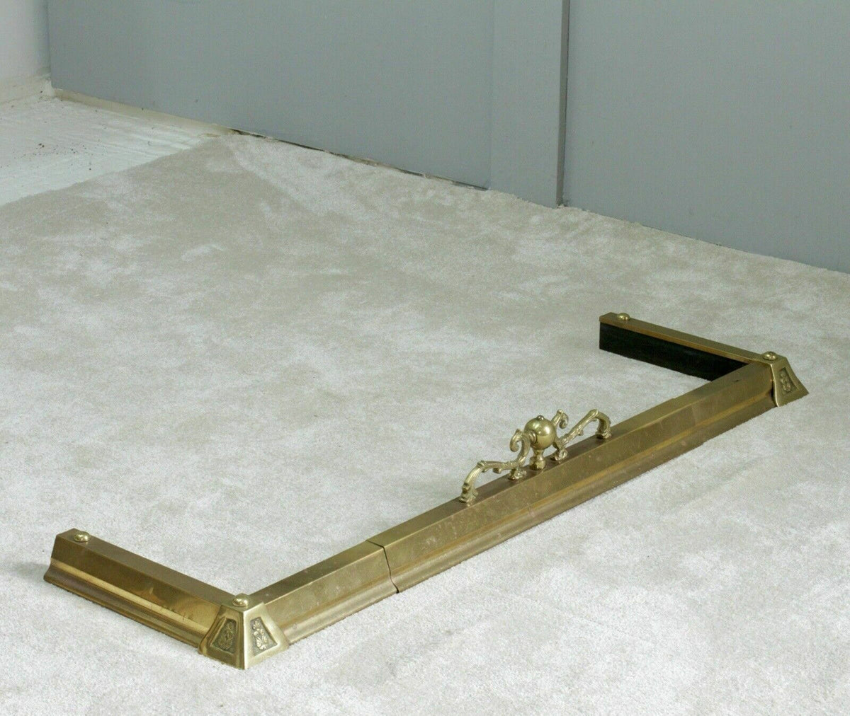 French antique brass fireplace fender, three-quarter view on carpet