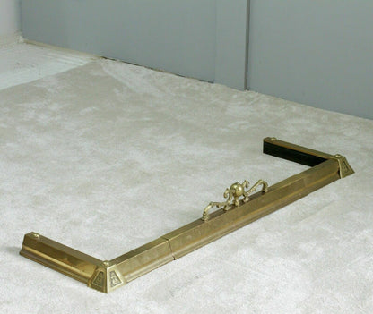 French antique brass fireplace fender, three-quarter view on carpet