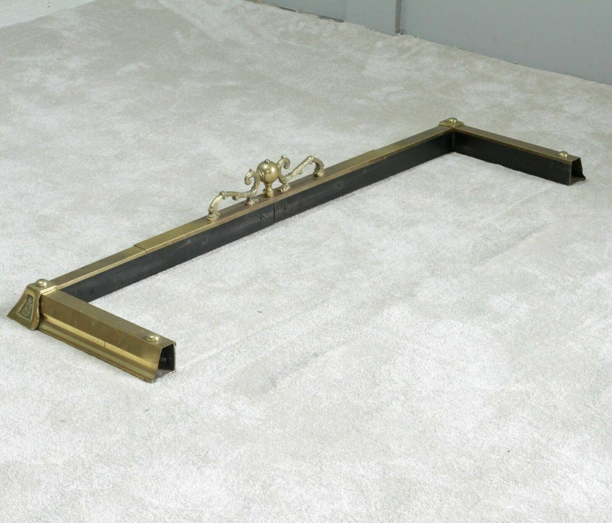 Brass fireplace fender showing black-painted underside rail