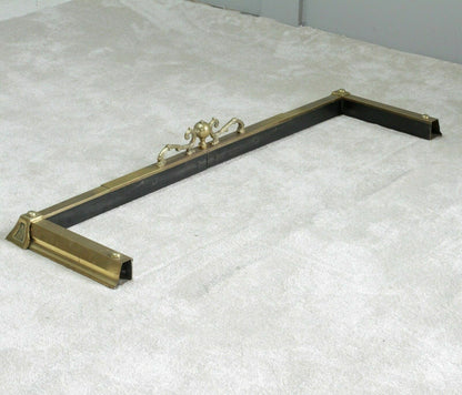 Brass fireplace fender showing black-painted underside rail