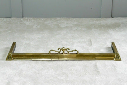 French antique brass fireplace fender on a cream carpet, front view