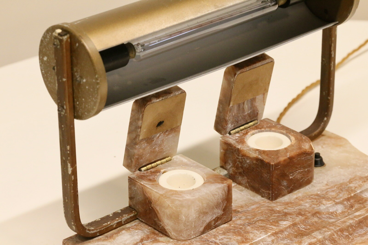 Close-up of open alabaster inkwells beneath the brass shade