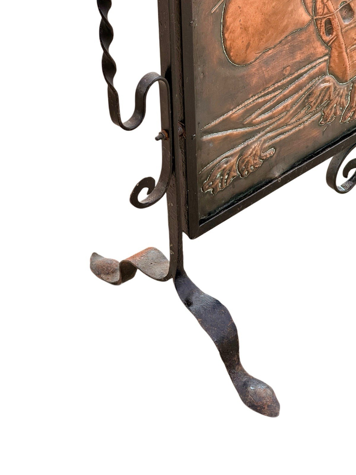 Close-up of wrought iron splayed foot and copper sea panel, fire screen