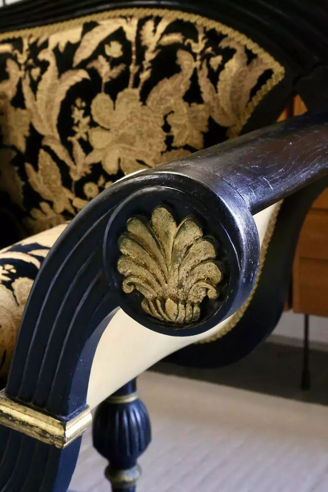 Close-up of carved gilt anthemion on the ebonised arm