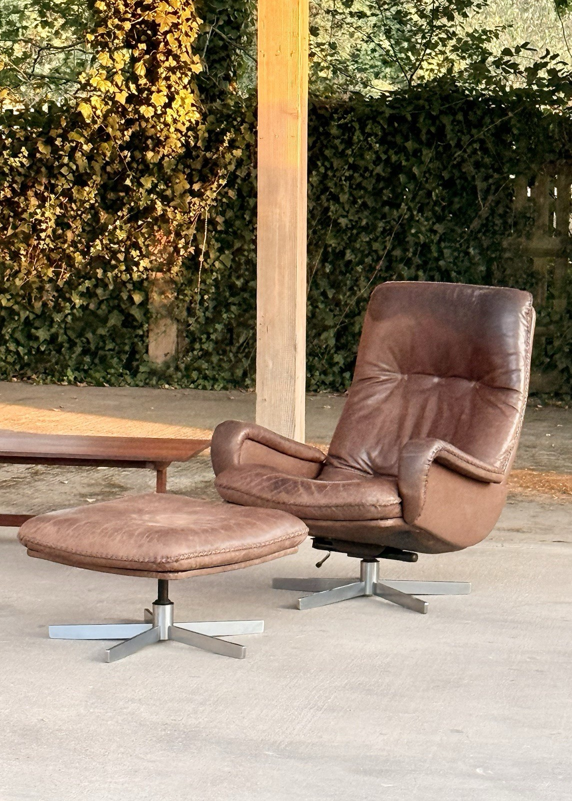 De Sede S231 brown leather lounge chair and ottoman in a garden setting