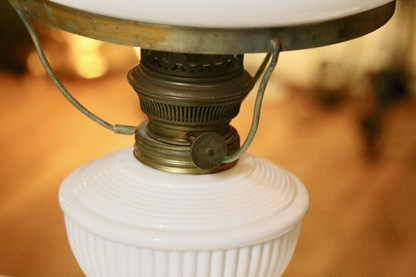 Close-up of brass burner with wick wheel on milk glass font