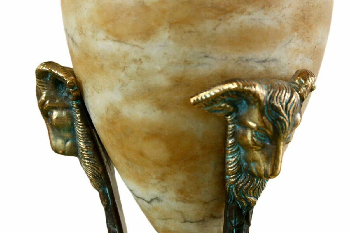 Close-up of brass ram's head mounts on the alabaster urn