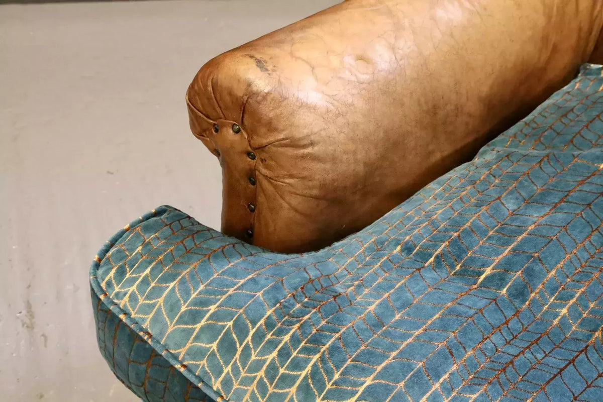 Close-up of scrolled leather arm and teal and copper velvet cushion