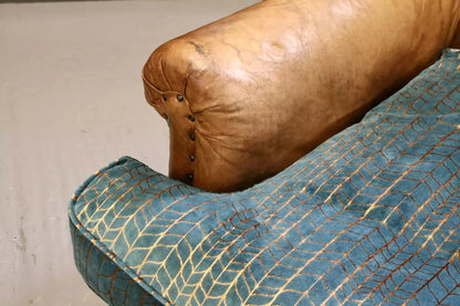 Close-up of scrolled leather arm and teal and copper velvet cushion