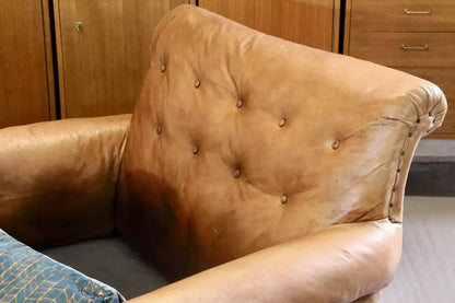 Close-up of button back and scrolled crest rail in brown leather