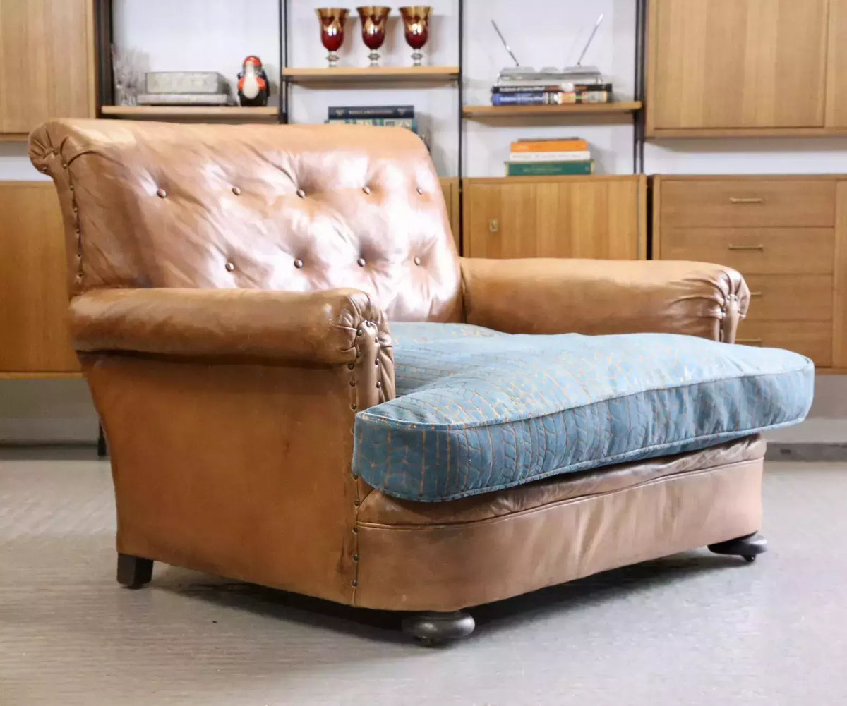 French Art Deco style brown leather loveseat with studded button back, scrolled arms and teal and copper velvet cushion