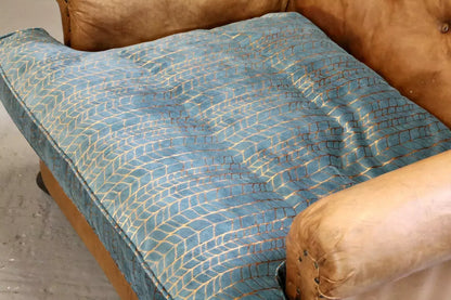 Close-up of teal and copper velvet seat cushion and leather arm