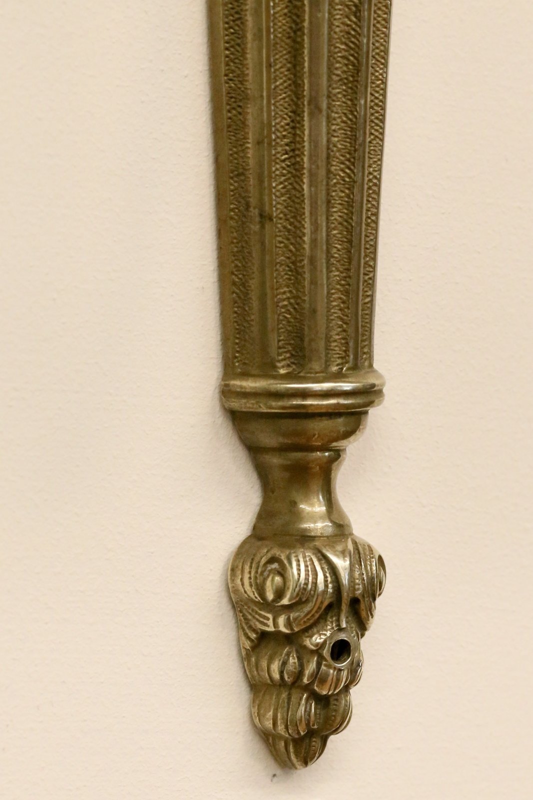 Close-up of the foliate drop finial on the brass sconce
