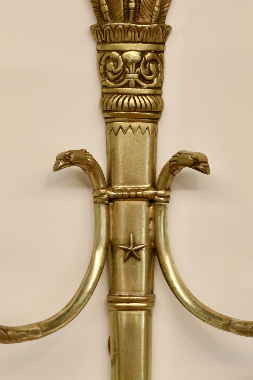 Close-up of swan head arm mounts and star motif on the sconce backplate