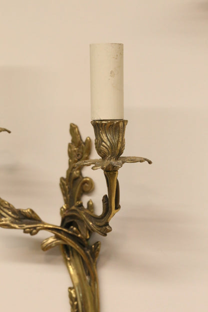 Close-up of scrolling leaf arm and candle sleeve, gilt brass sconce