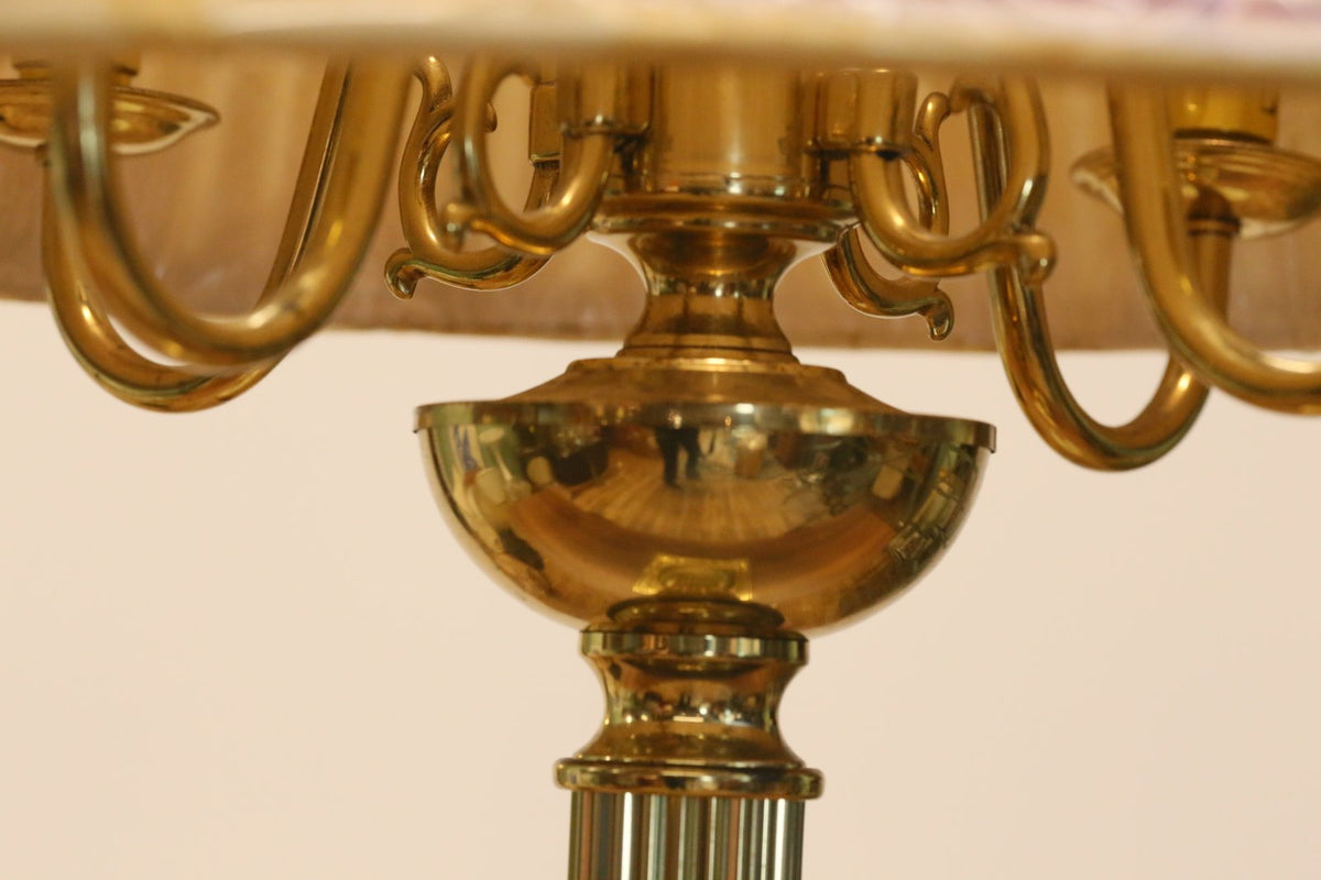 Close-up of brass scrolled arms and urn under the shade