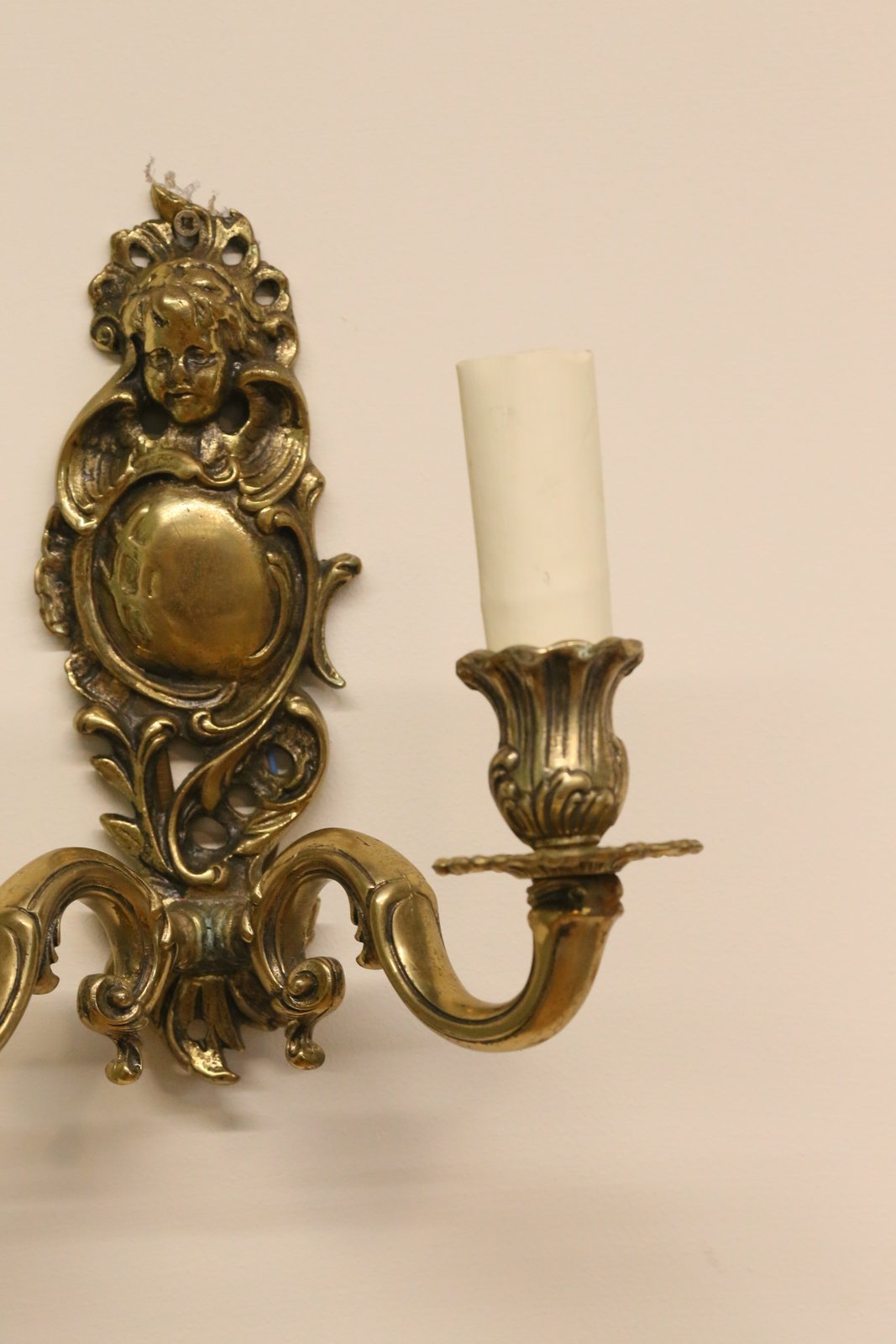 Close-up of cherub crest and scrolled backplate, Italian brass sconce