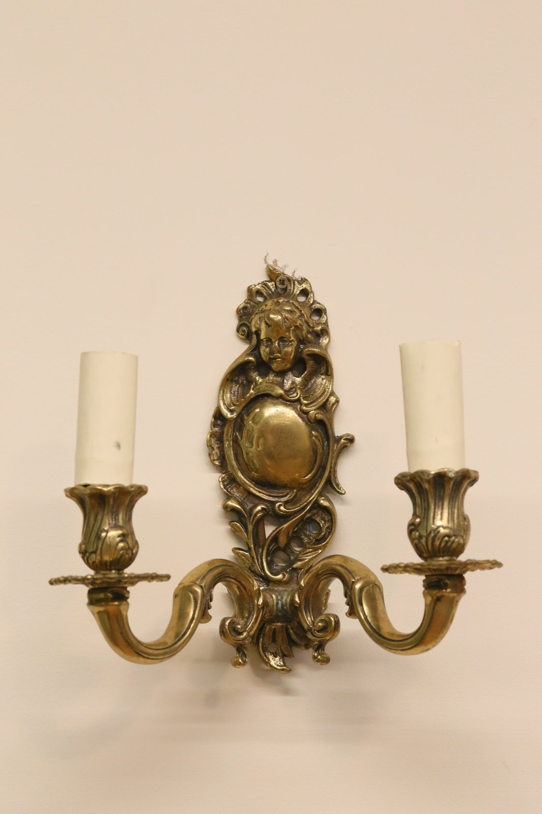 Italian brass cherub wall sconce with cast cherub face crest, foliate scroll backplate and two arms, H23cm