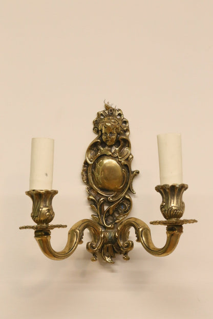Italian brass cherub wall sconce with cast cherub face crest, foliate scroll backplate and two arms, H23cm
