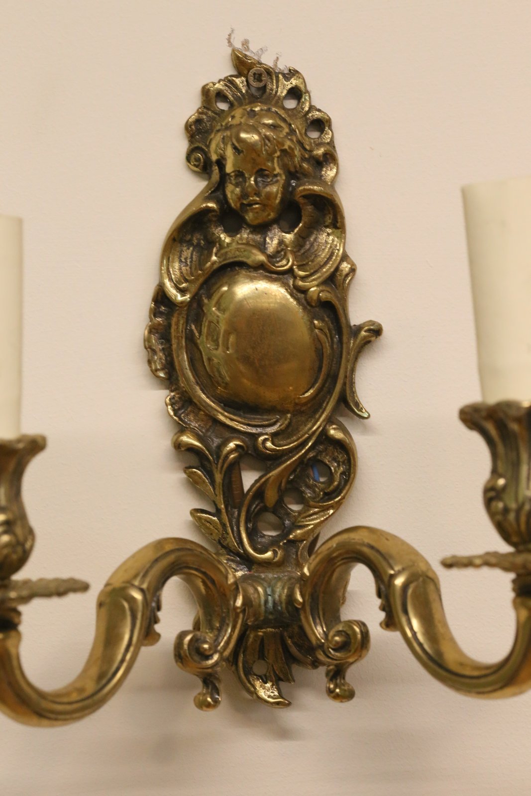 Close-up of cast cherub head and foliate scrolls, Italian brass sconce