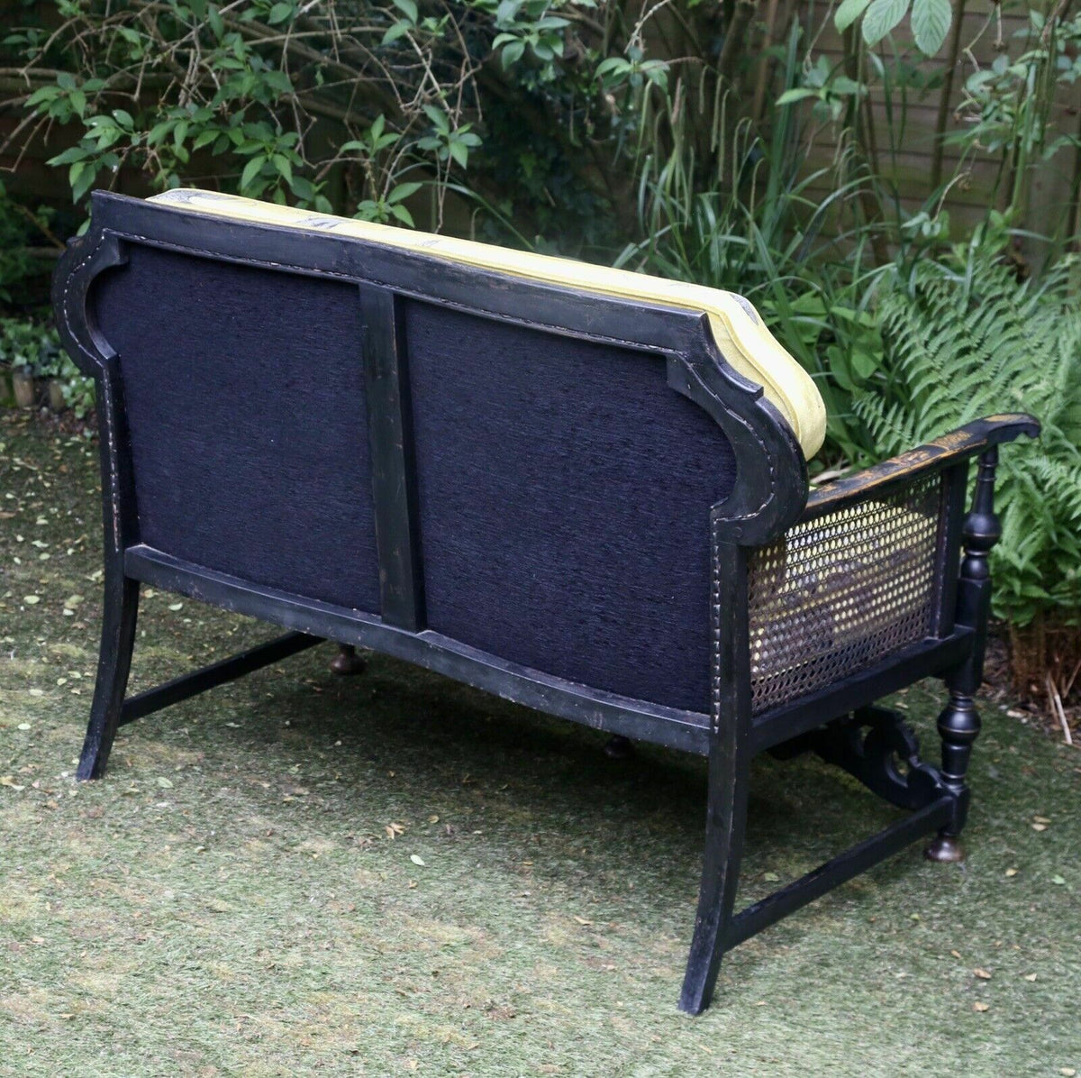 Back view of the chinoiserie sofa showing upholstered back and caned side
