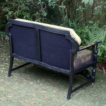 Back view of the chinoiserie sofa showing upholstered back and caned side