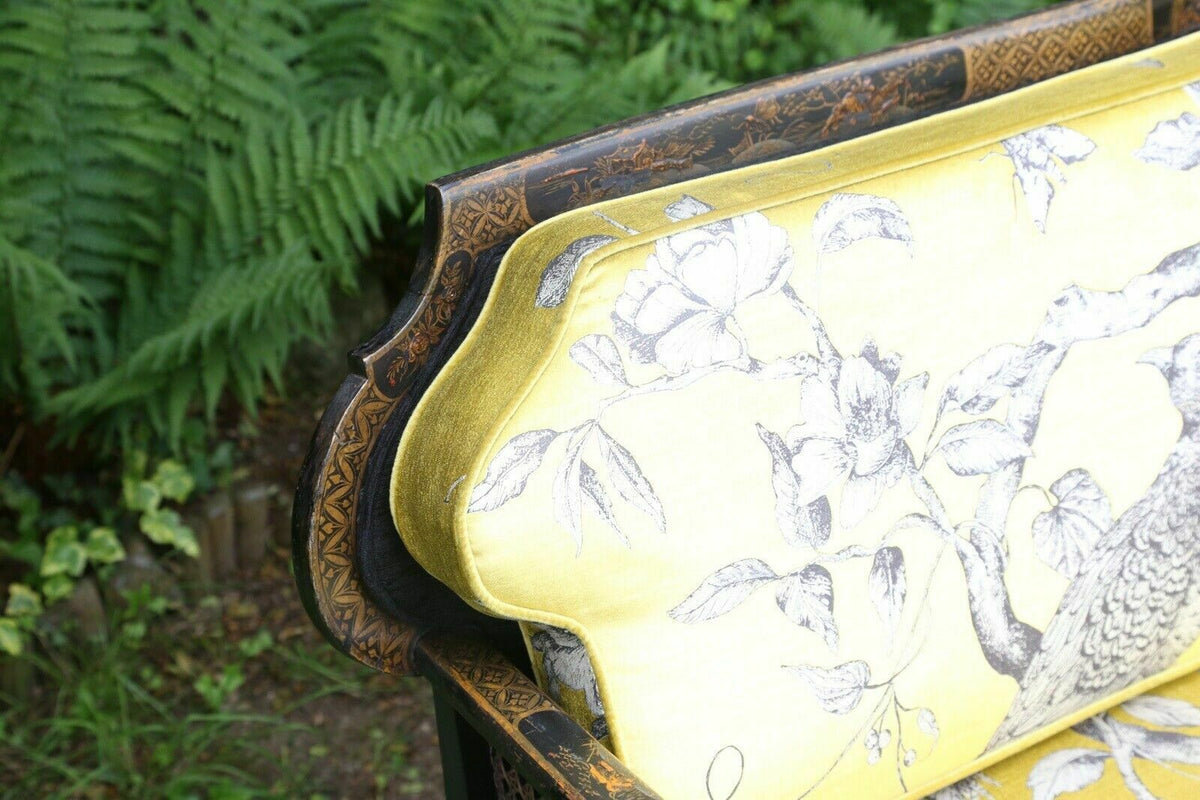 Close-up of gilt chinoiserie top rail and yellow bird-print back cushion