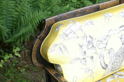 Close-up of gilt chinoiserie top rail and yellow bird-print back cushion