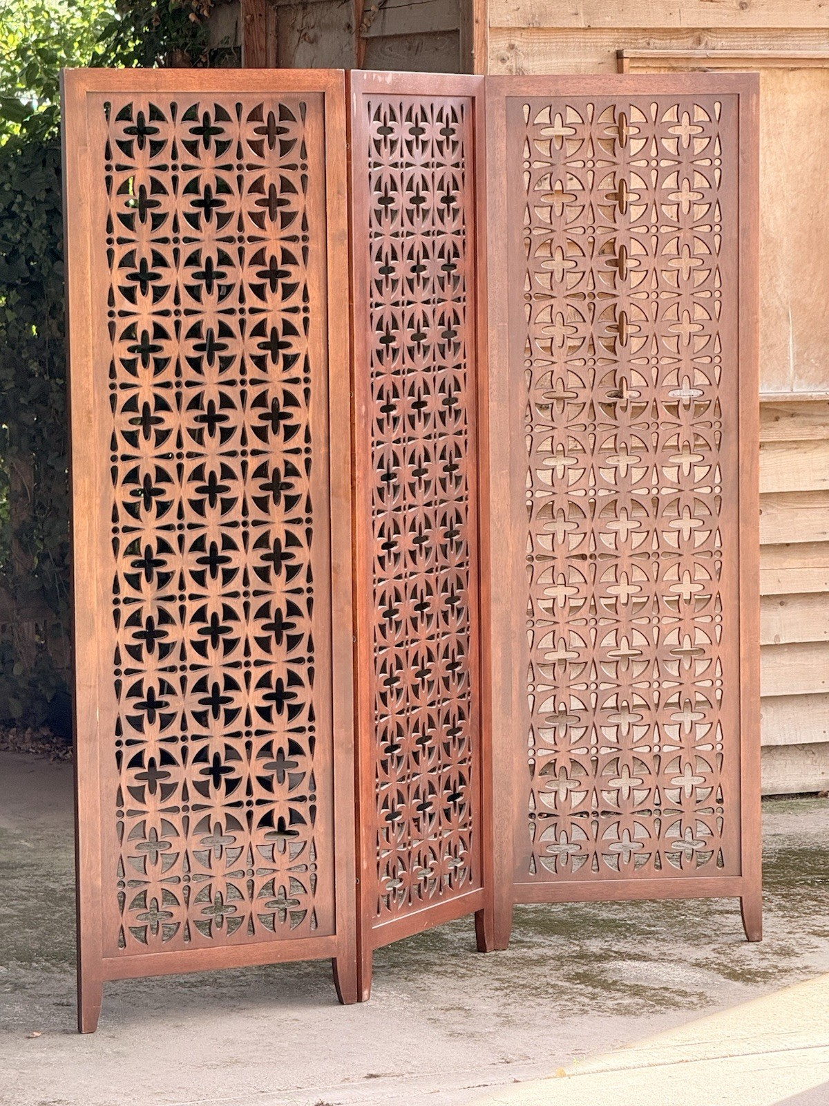 Teak pierced screen with light coming through the panels