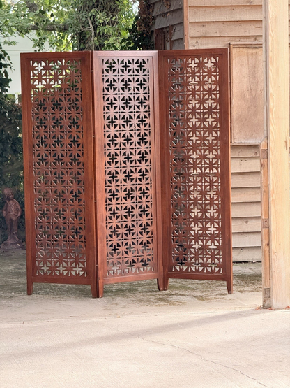 Mid-century solid teak three-panel pierced screen, three-quarter view outdoors