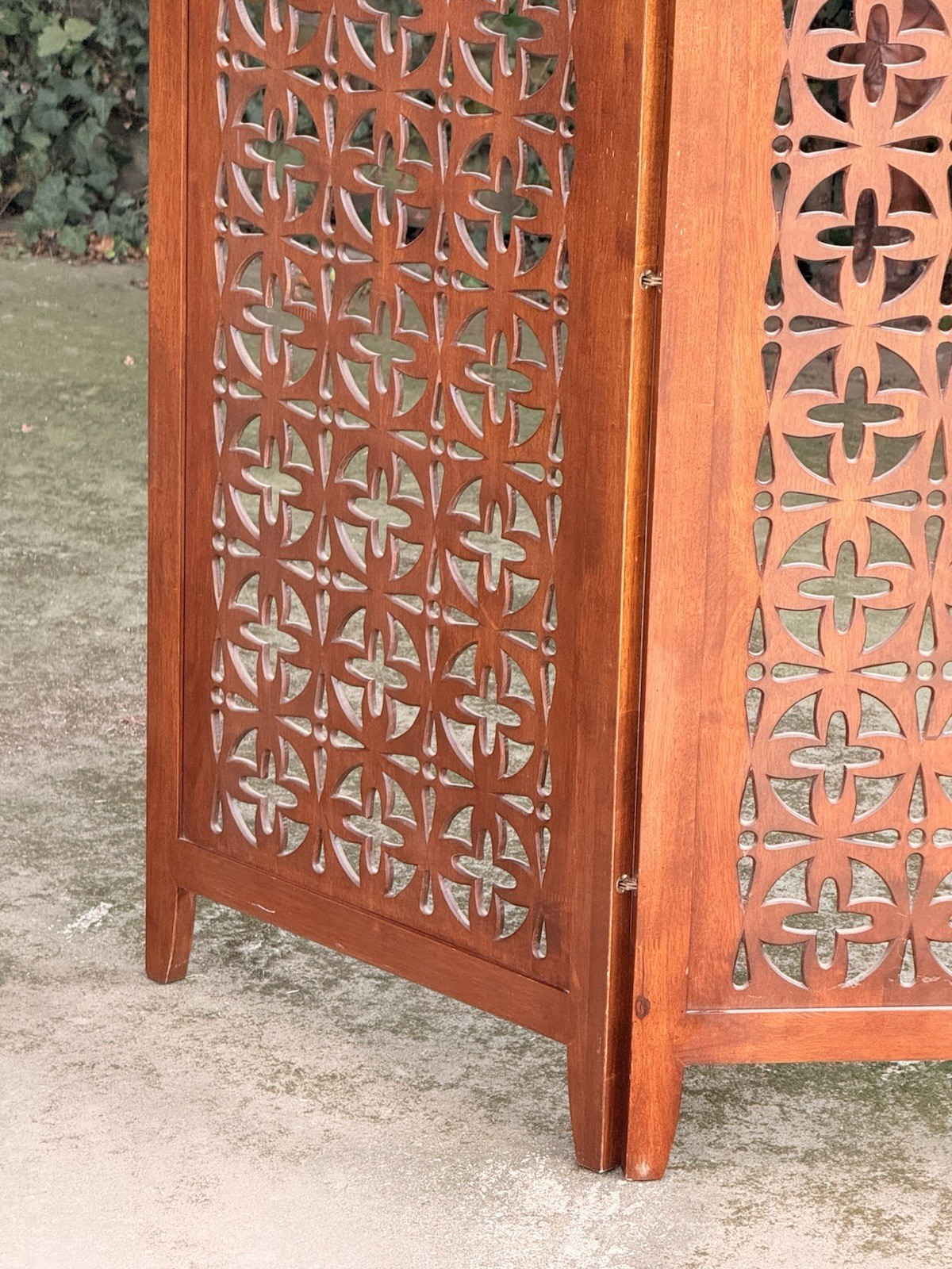 Close-up of pierced geometric pattern and panel feet, teak screen