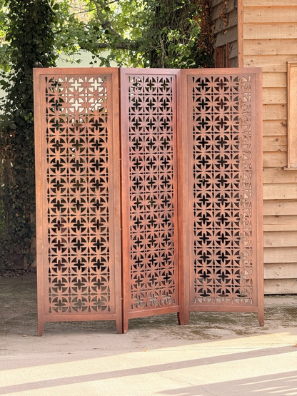 Mid-century solid teak three-panel pierced screen, front view in sunlight