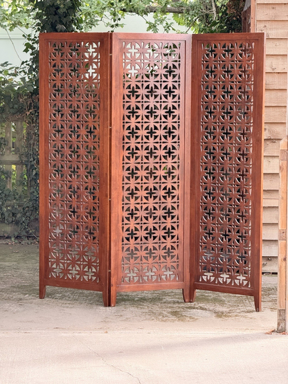 Mid-century solid teak three-panel pierced screen, folded front view outdoors