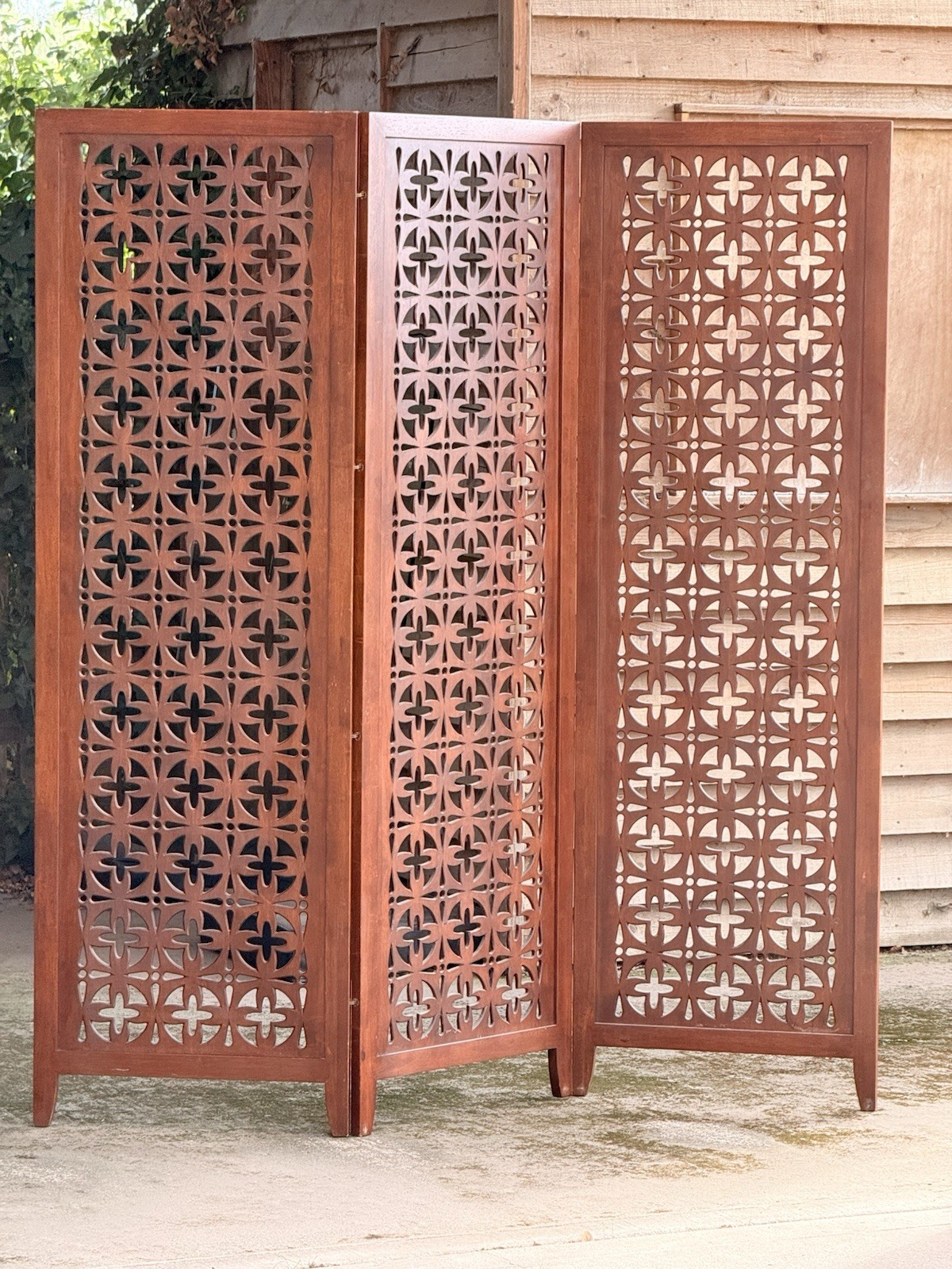 Mid-century solid teak three-panel pierced screen outdoors, front view