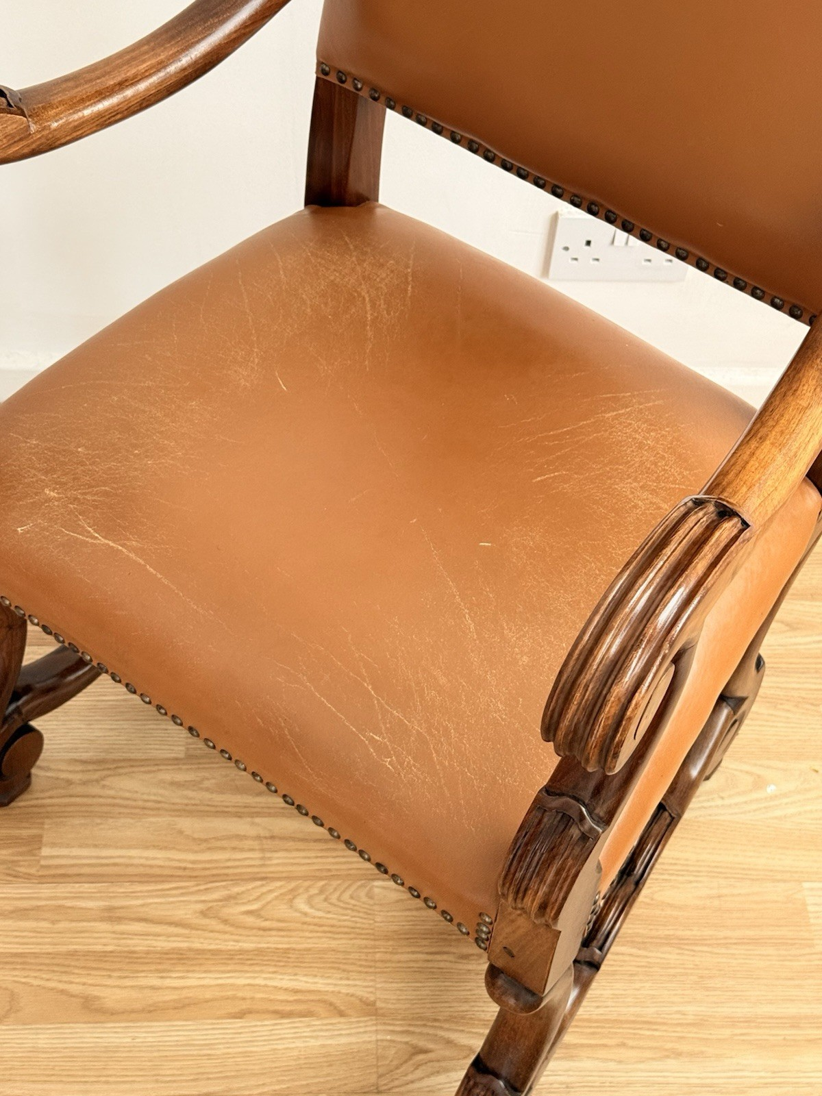 Close-up of leather seat and carved scrolled arm