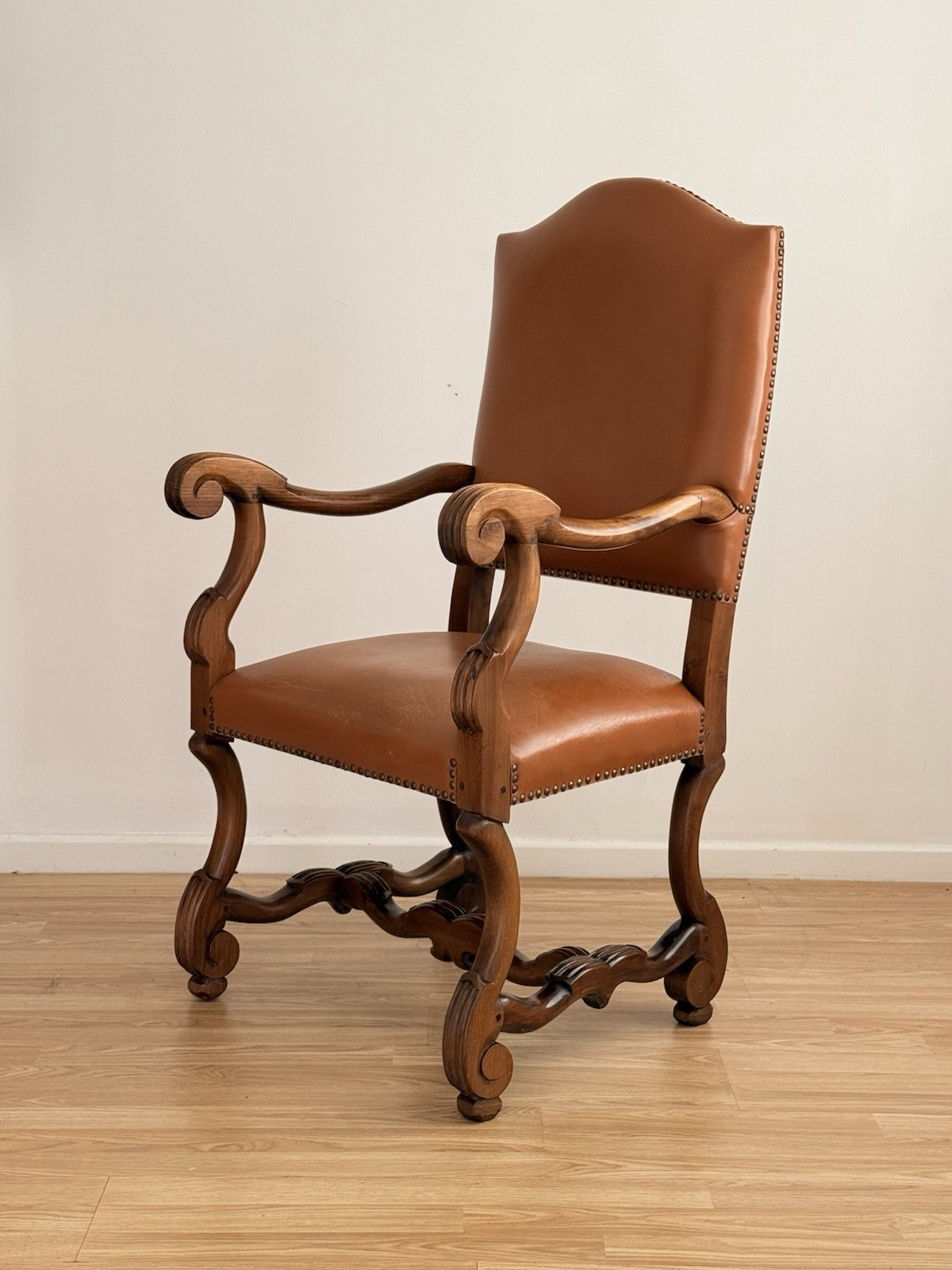 Spanish Baroque Revival carved wood and leather armchair, three-quarter view from the left