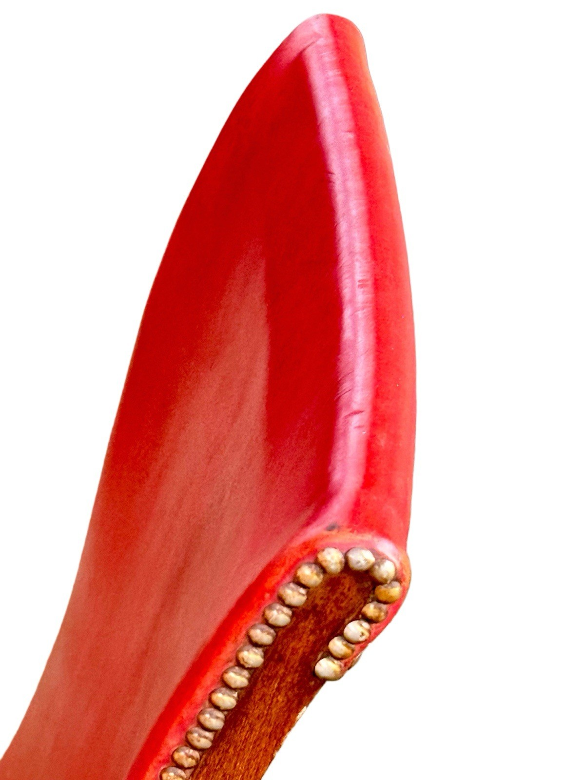 Close-up of the curved red leather backrest edge with brass studs