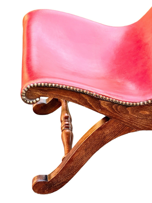 Close-up of curved red leather seat with brass nailhead trim and beech frame