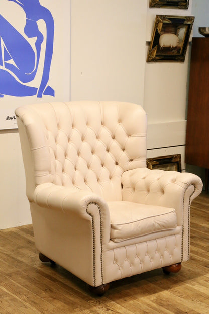 Cream leather Chesterfield wing armchair, three-quarter view in a room setting