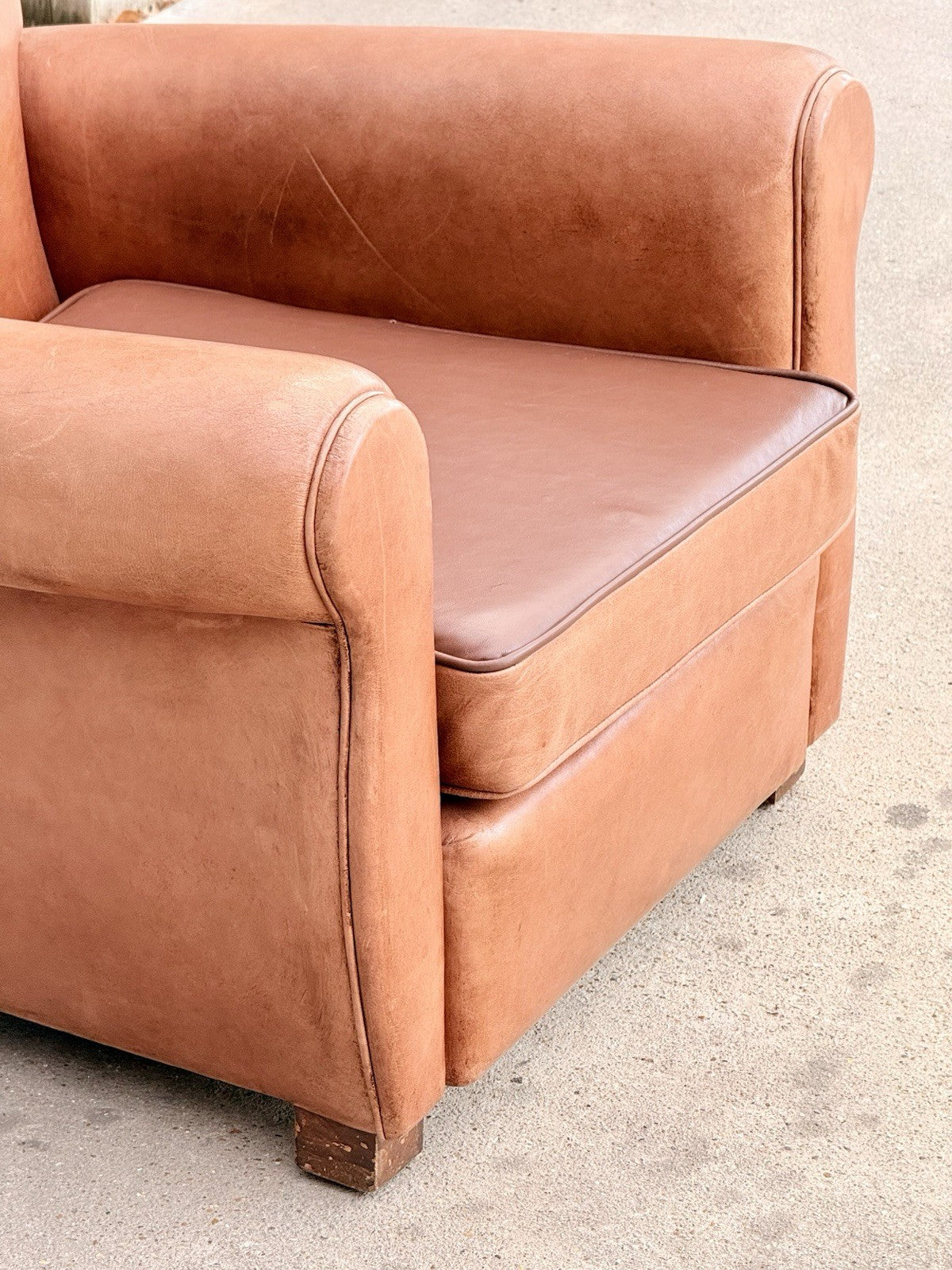Close-up of seat cushion and rolled arm, tan leather club chair