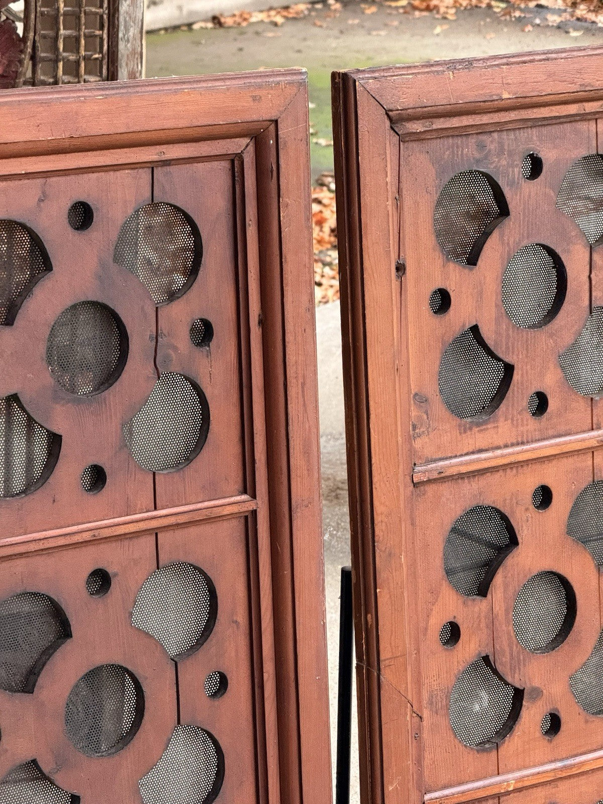 Close-up of pierced quatrefoil and circle cutouts with mesh behind