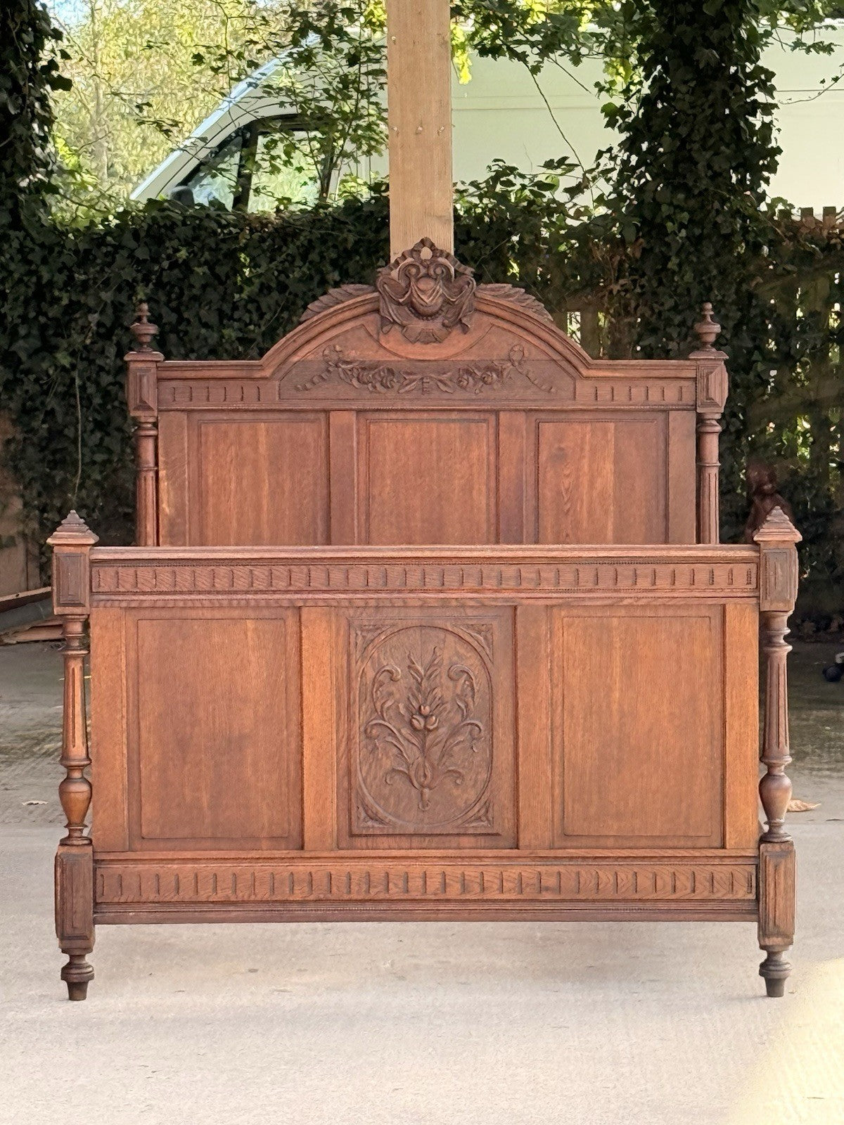 Henri II carved oak footboard in front of matching headboard